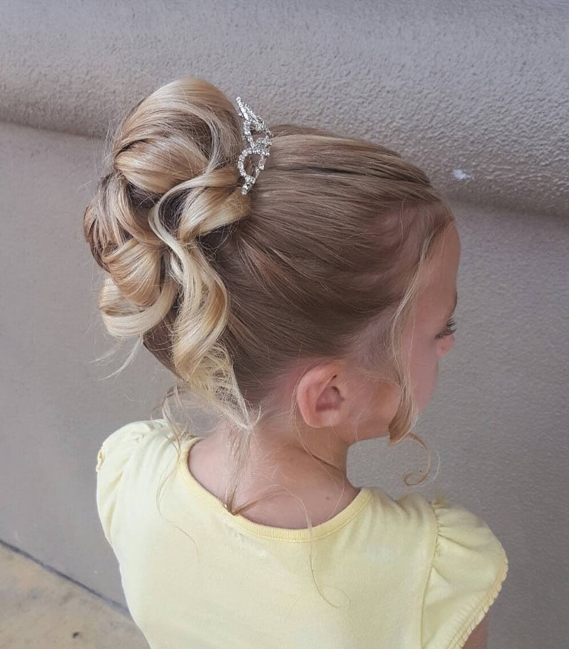 9 year old girl with a loose curly updo featuring a sparkly tiara.