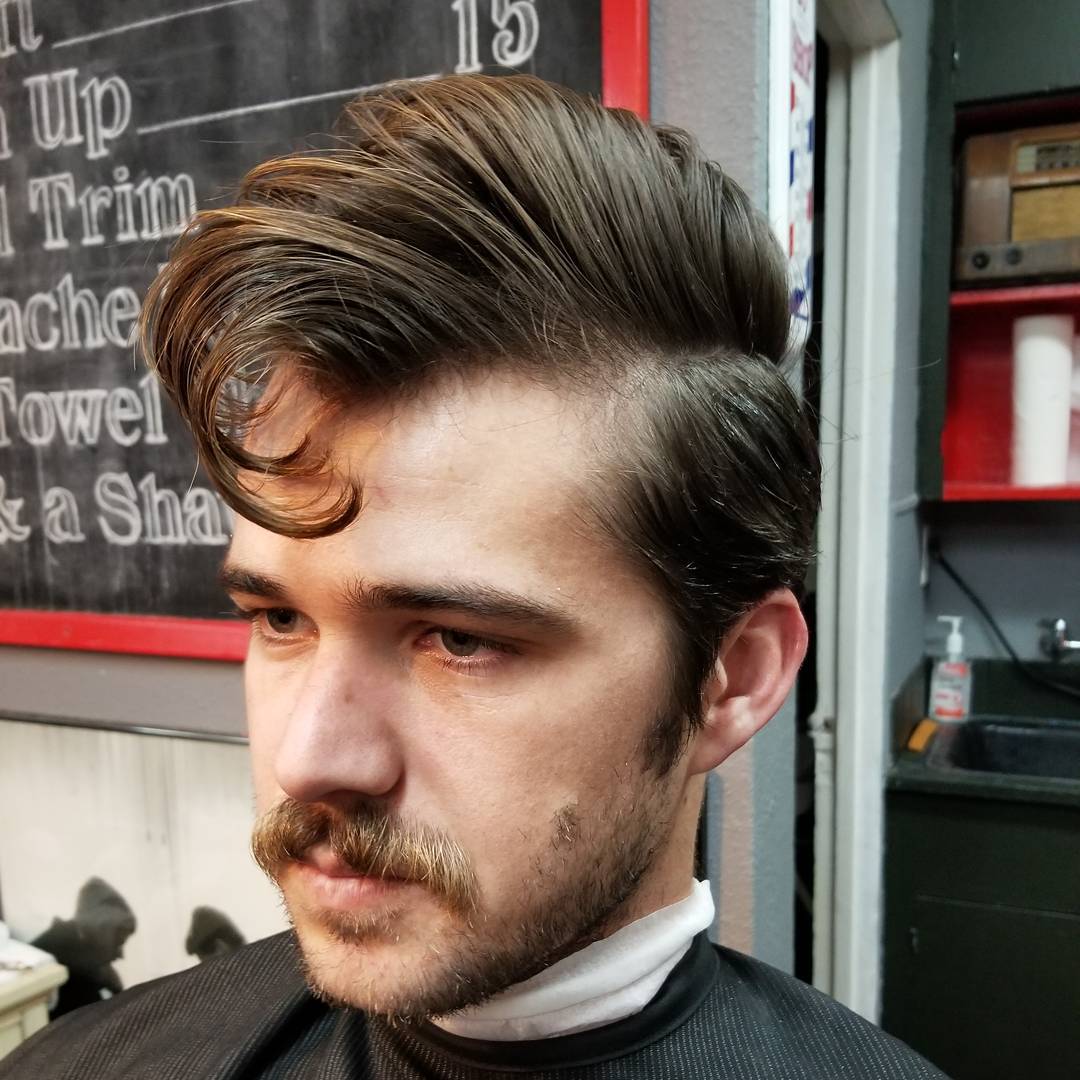 classic 1950s inspired greaser hairstyle with a side part, curved front quiff