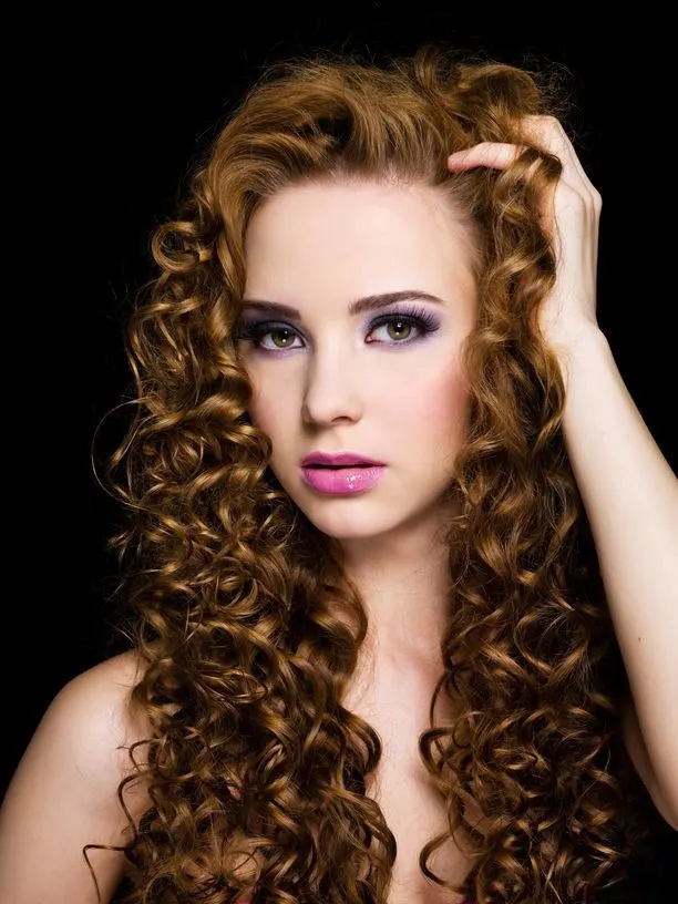 Portrait of a beautiful woman with long curly hairs - On a black background