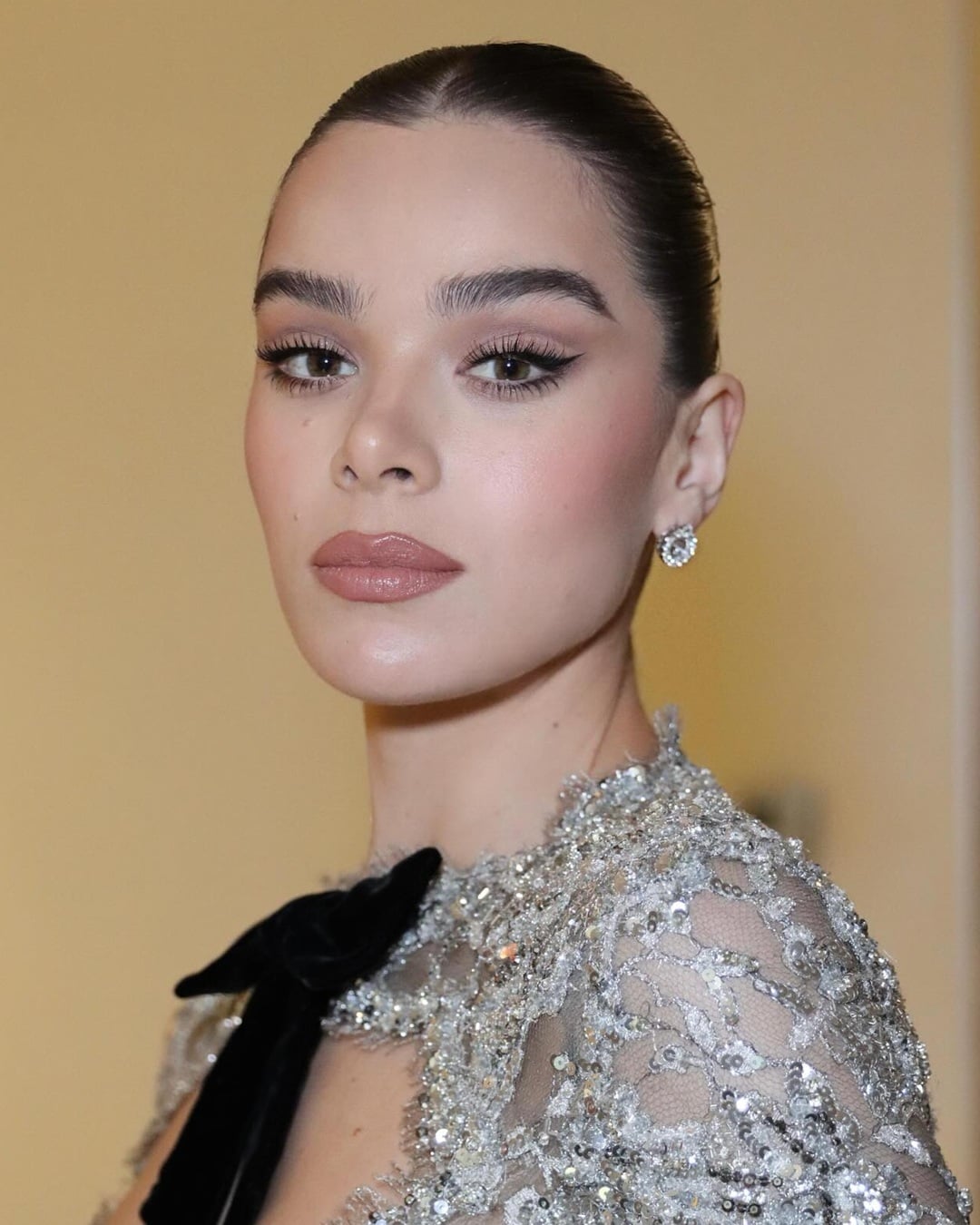 Actress Hailee Steinfeld with sleek black hair in a pulled-back updo and brown eyes