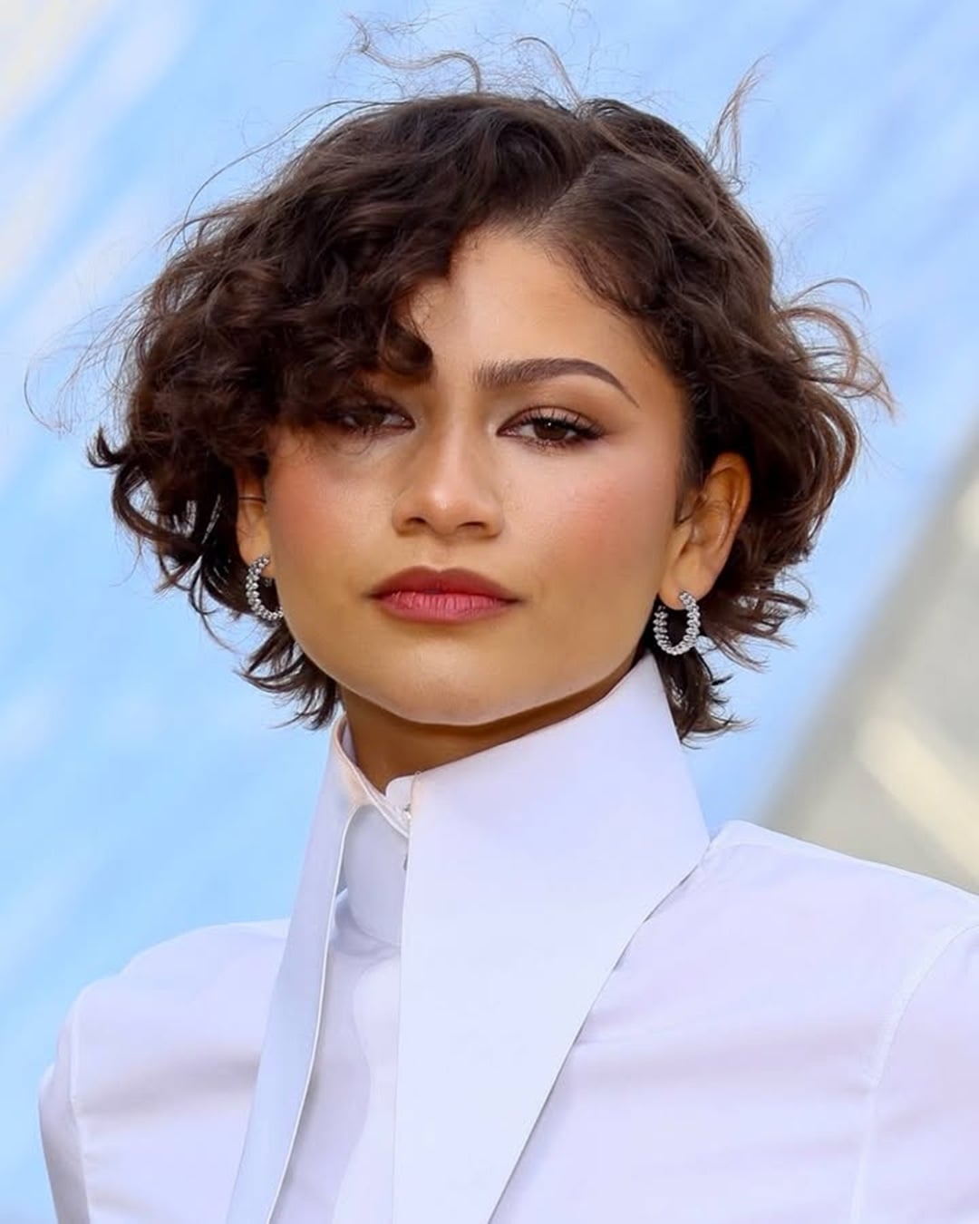 Actress Zendaya Coleman sporting a short brown curly bob with natural defined ringlets and a side part