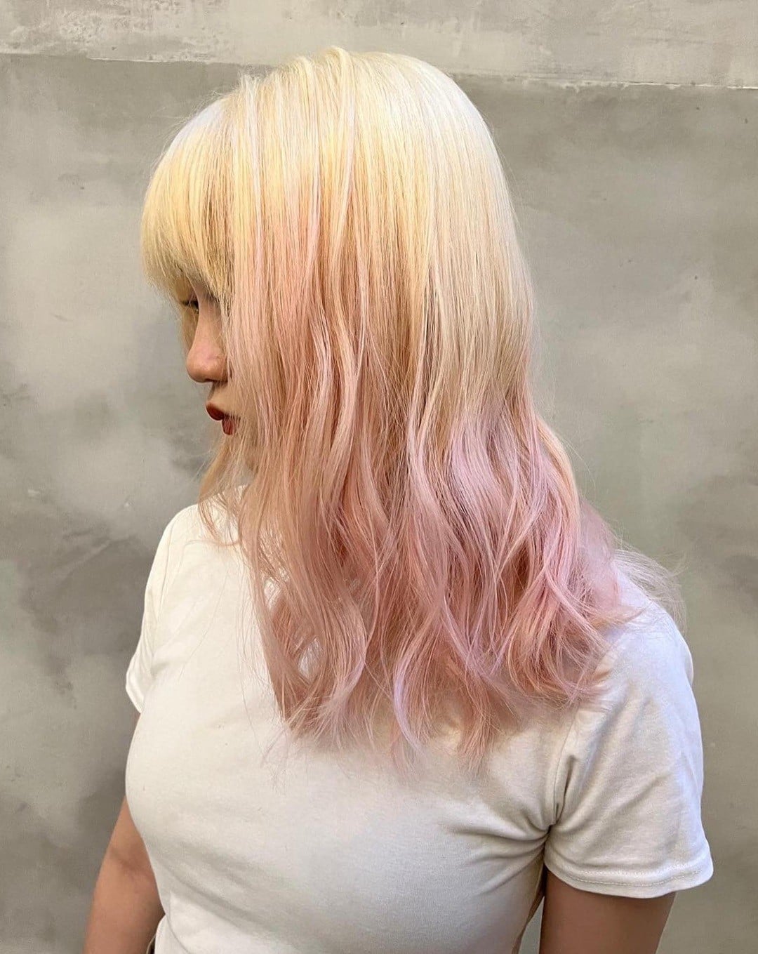 Asian woman with blonde to pastel pink ombre hair and wispy bangs