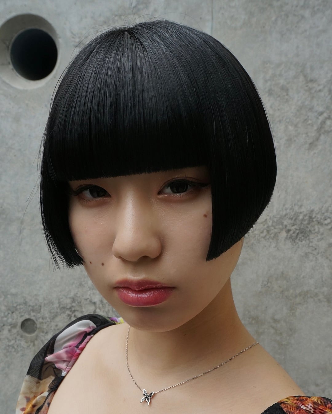 Sharp blunt Asian bob cut with straight full bangs on sleek jet black hair.