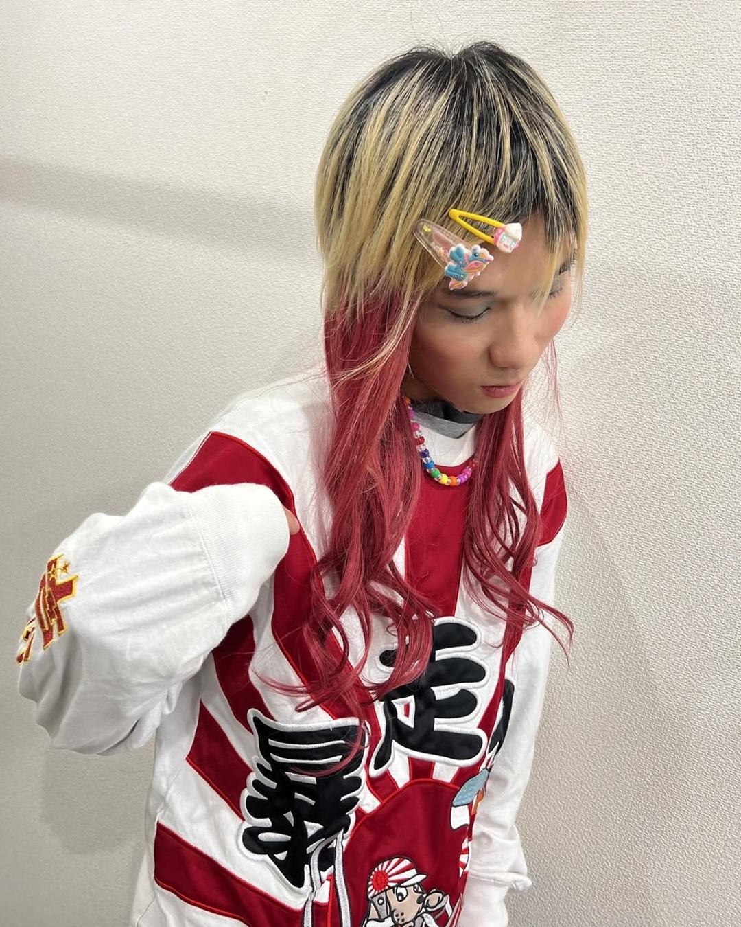 Asian girl with berry red peekaboo hair extensions underneath blonde layered hair