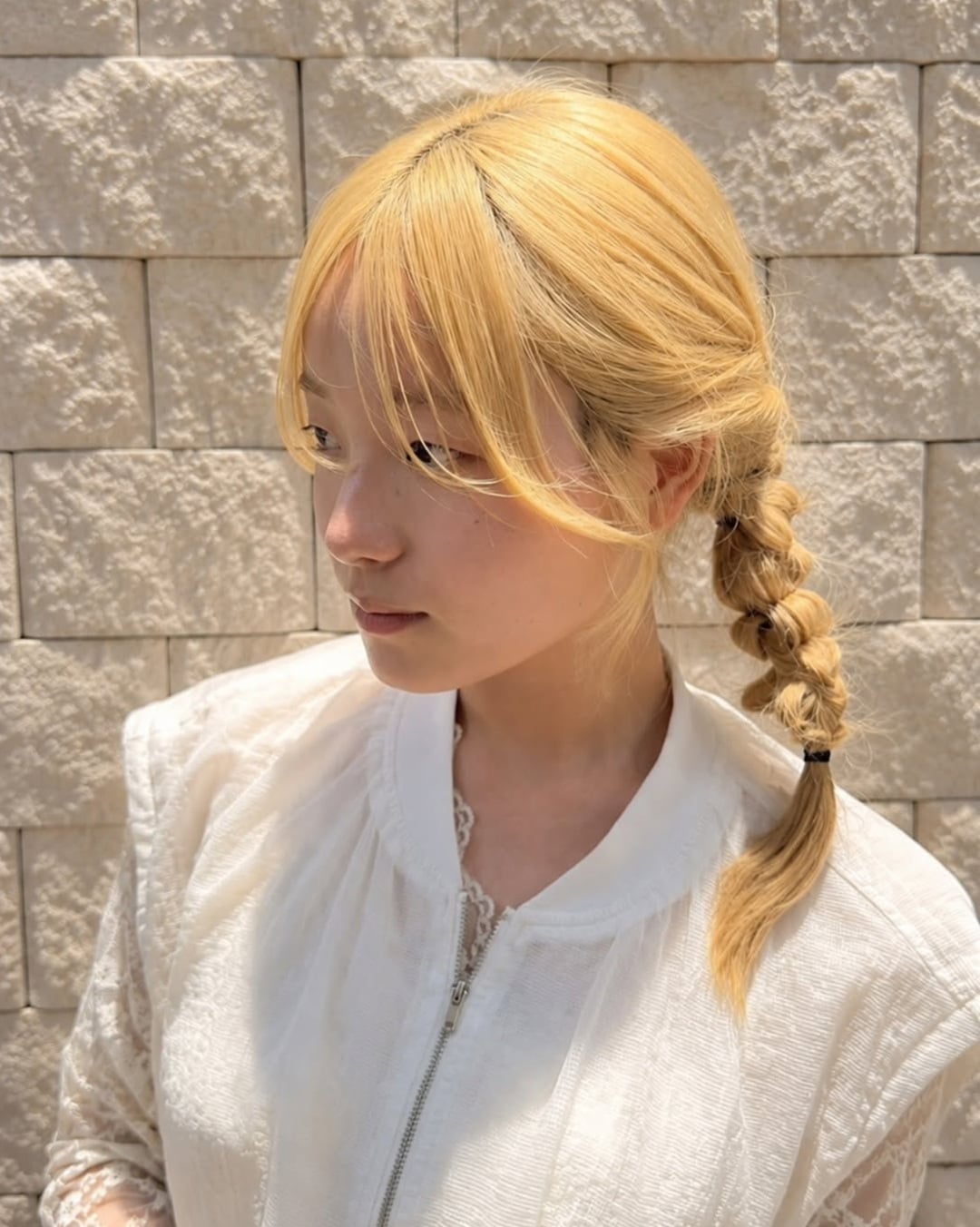 Asian woman with honey golden blonde hair in a side braid with bangs