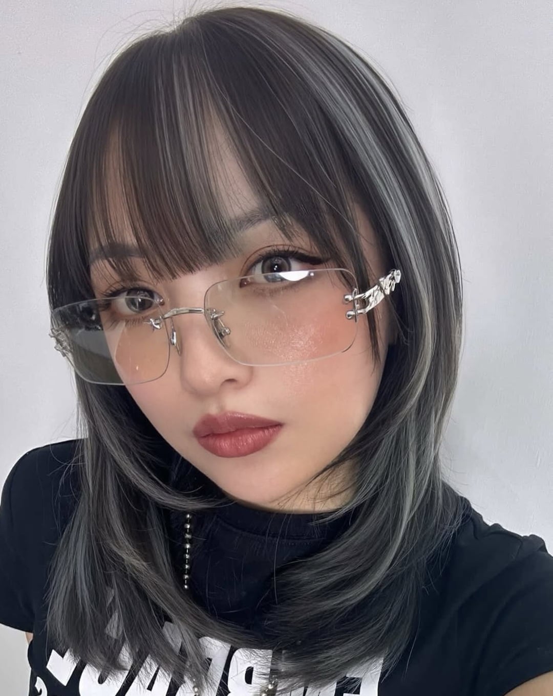 Asian woman with dark layered hair full bangs and silver gray highlights