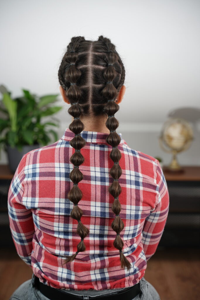 Back view of the finished double bubble braid pigtails with even bubbles and lace braid detail on both sides.
