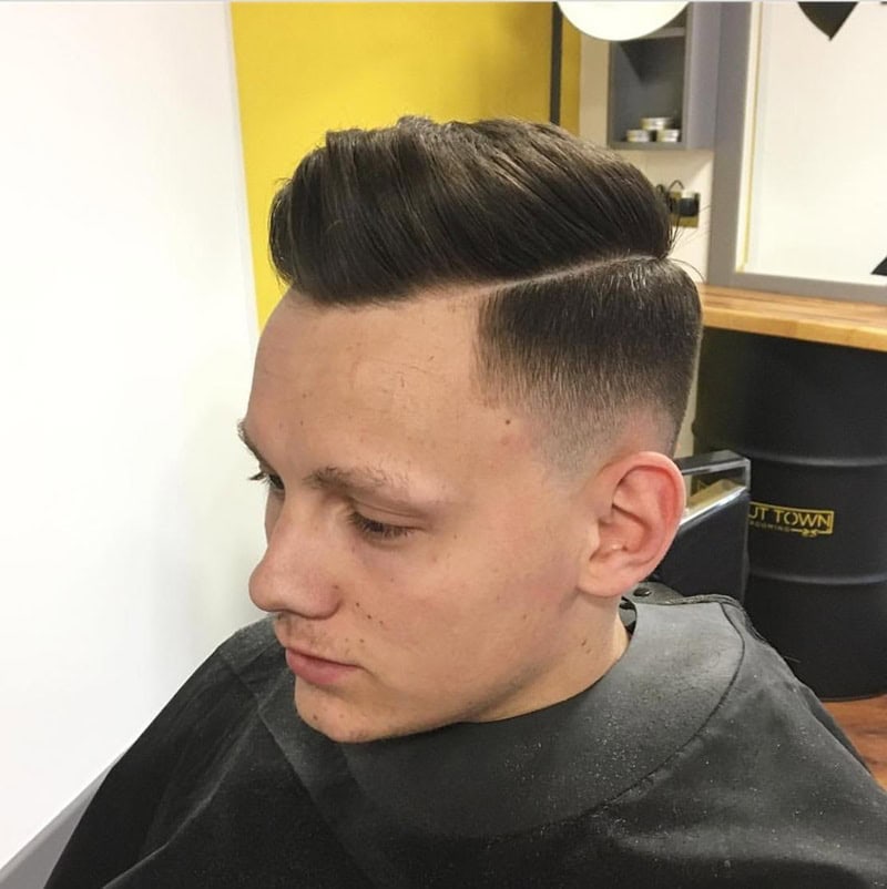 dark hair styled into a pompadour with a crisp razor line