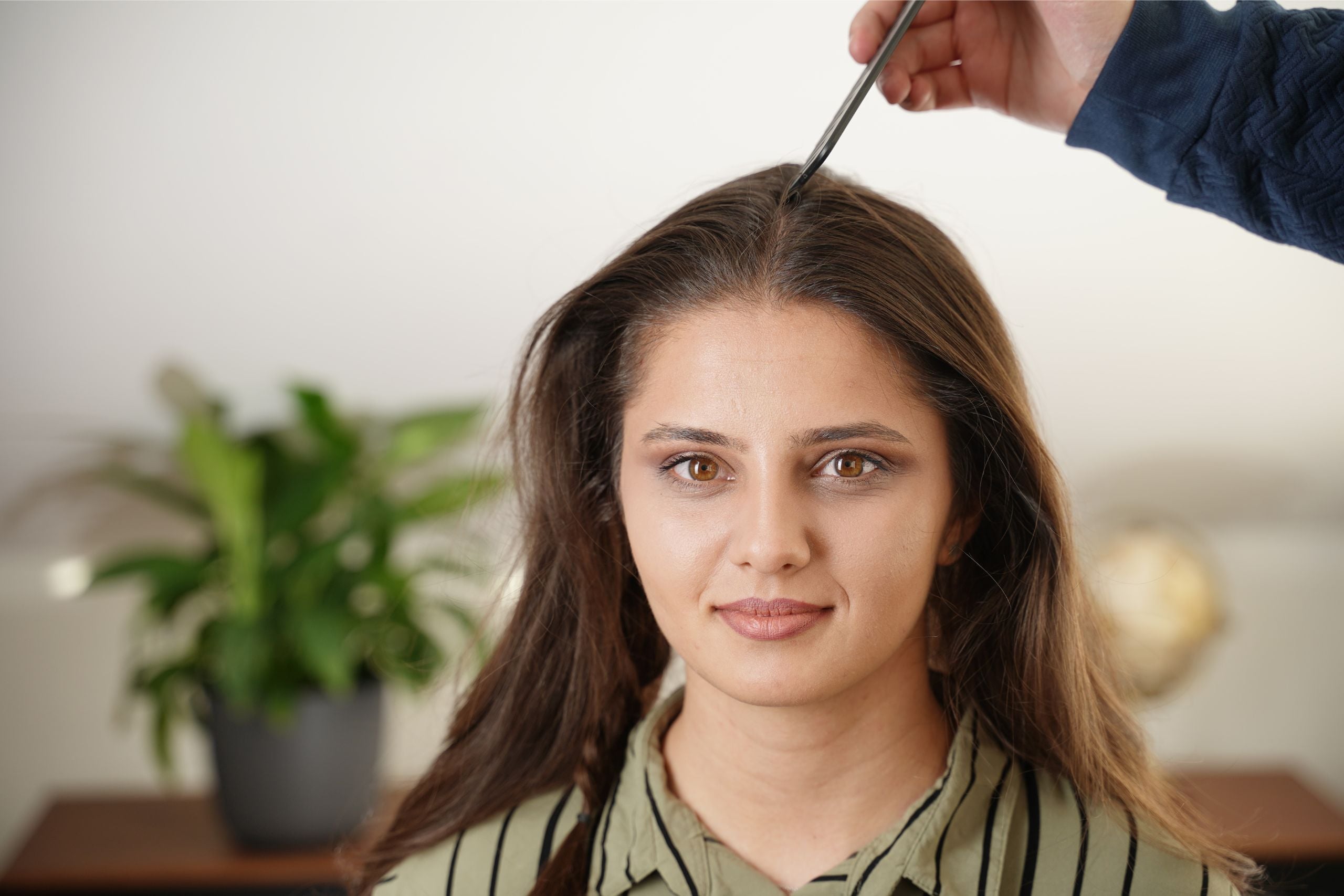Creating a clean center part in the front section of the hair using a comb.