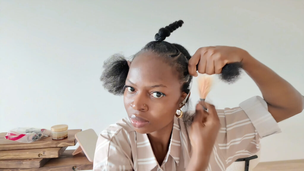 The stylist ties and twists the larger side section while leaving the thin side braid section loose.