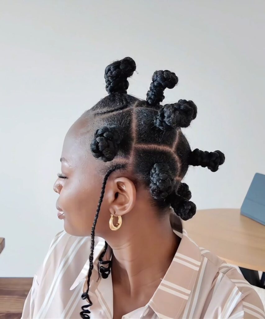 Side view of the finished Bantu knot hairstyle showing raised knots, curved parts, and a slim side braid.