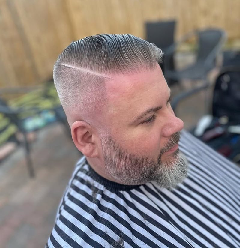 man with slicked comb over gray hair and high skin fade hard part