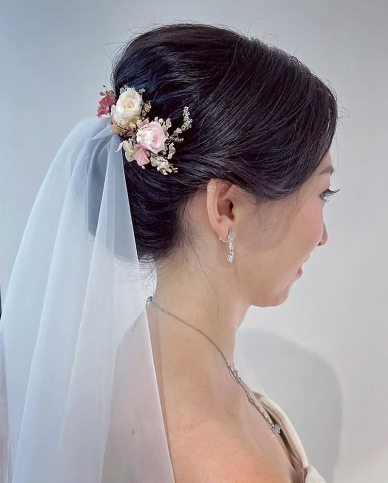 Japanese woman with a sleek low bun and a bridal veil