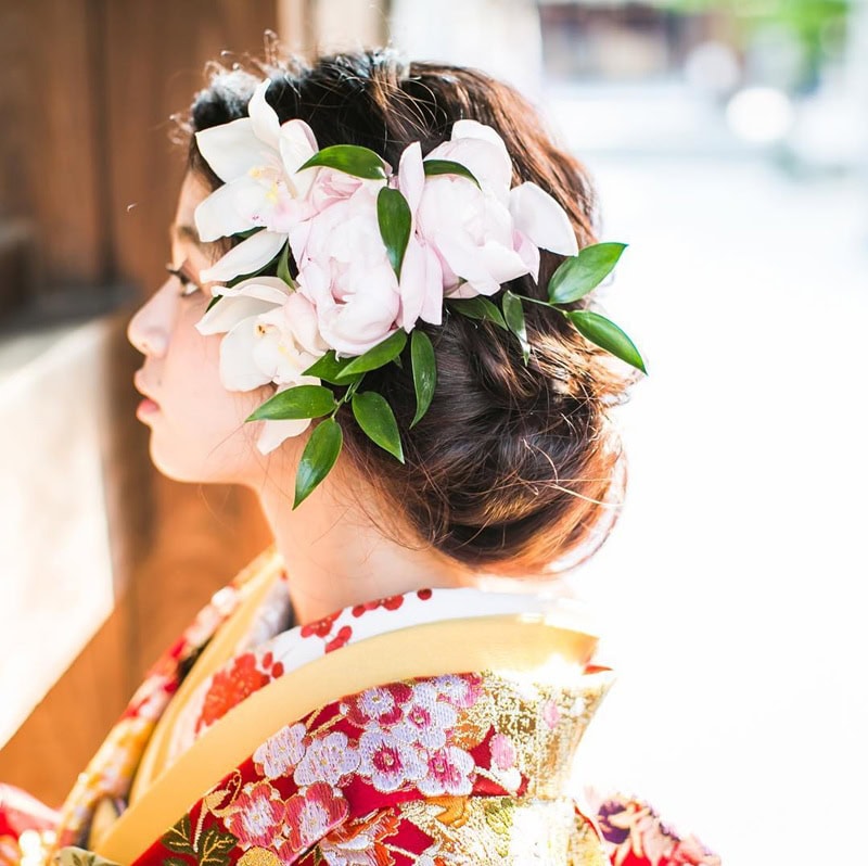Japanese woman wearing a textured low chignon bun decorated with peonies