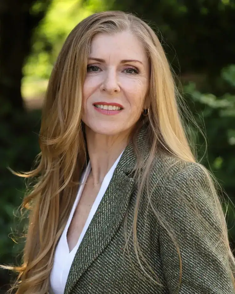 Older woman with hip-length layered strawberry blonde hair and a deep side part.