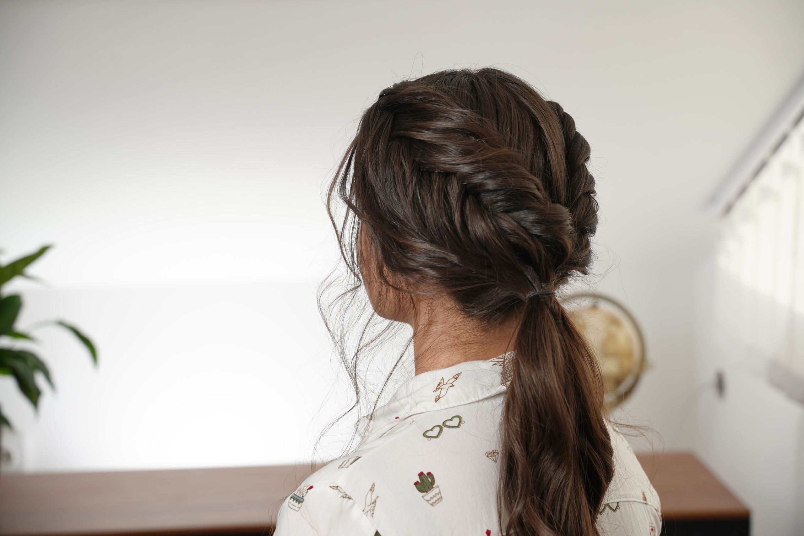 The loose hair, reverse fishtail braid, and flat twist gathered into a low ponytail before forming the bun.
