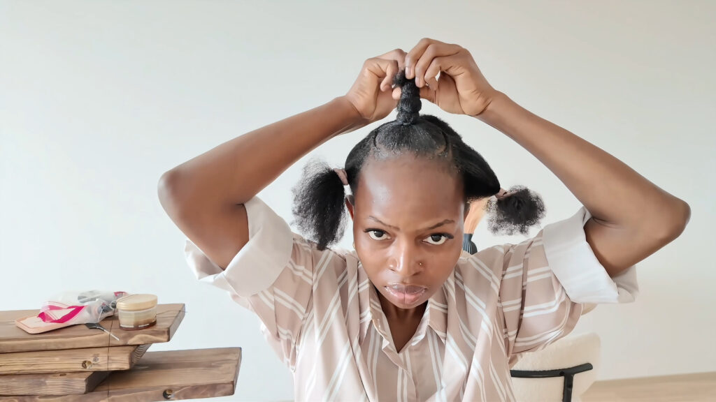 The stylist twists the loose hair above the tied front base
