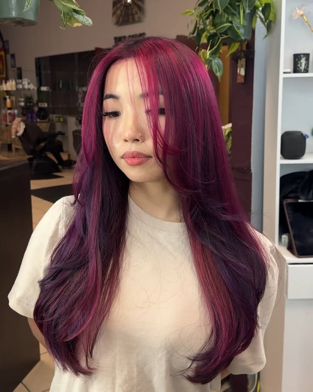 Asian woman with long layered dark hair and face framing berry magenta highlights