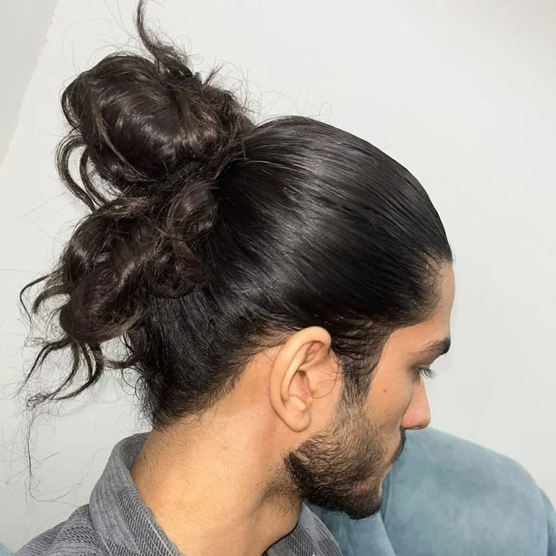 Dark-haired man wearing a high messy bun for managing long thick hair