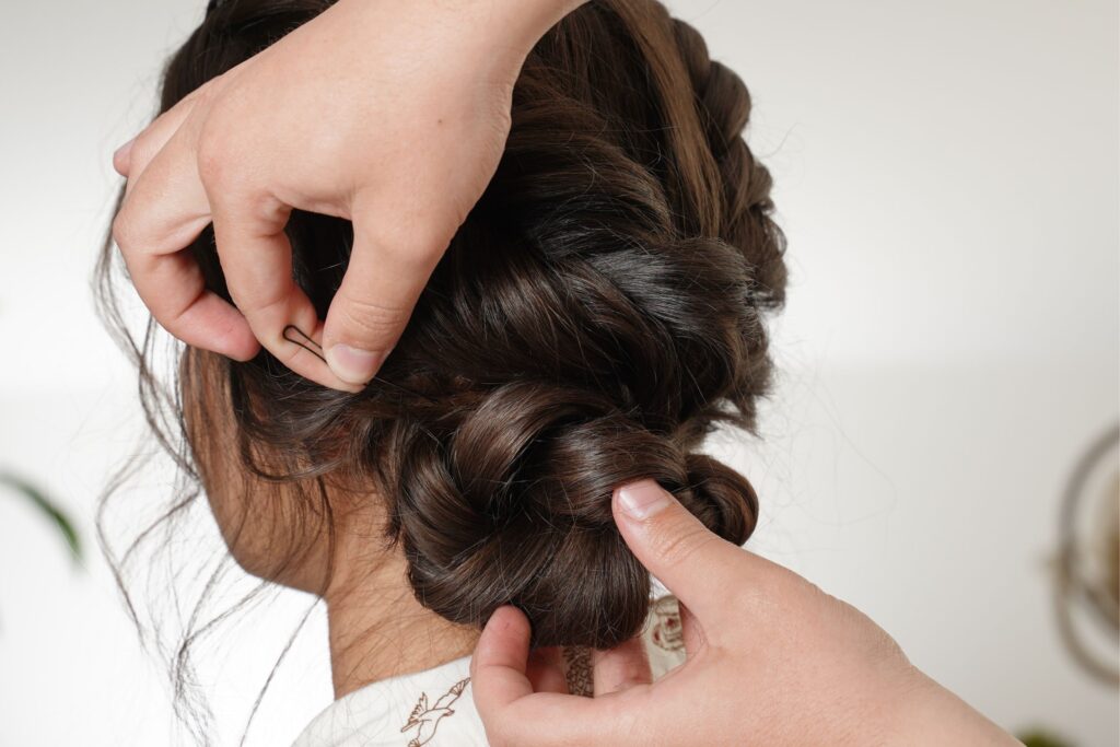 Stylist securing a wrapped low bun with bobby pins.