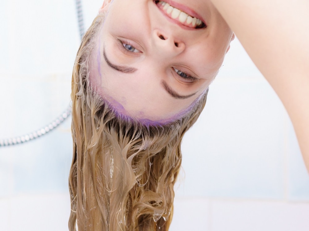 women with yellow hair  rinsing purple shampoo
