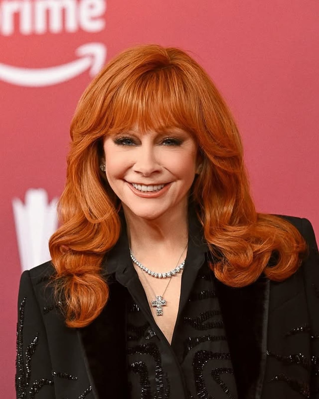 Reba McEntire long copper red hairstyle with full bangs and feathered layers