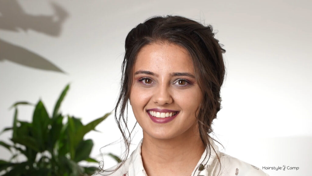 Front view of a soft low bun hairstyle with loose face-framing curls and braided detail.