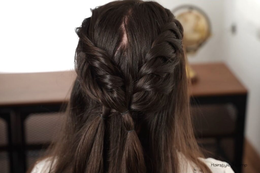 Back view of reverse fishtail braid and flat twist secured with small rubber bands before creating the low bun.