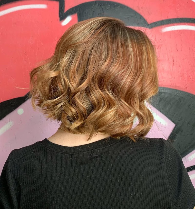 Wavy short bob with warm strawberry blonde highlights