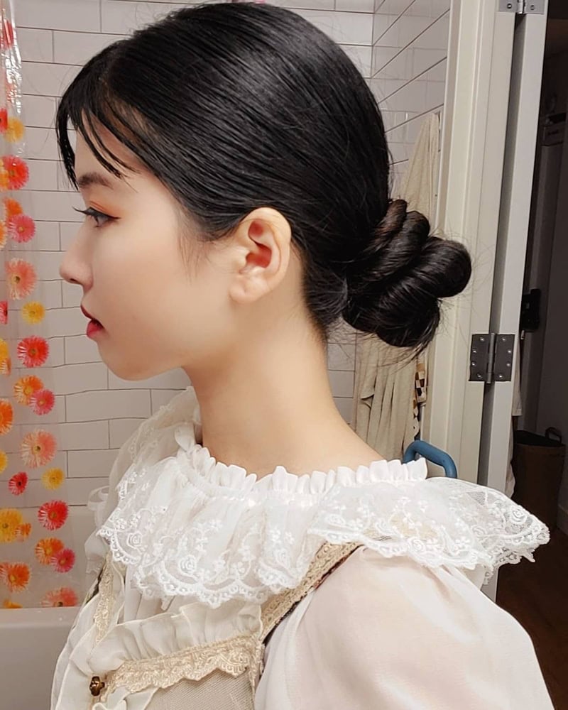 apanese woman with a minimalist low-twisted bun and soft front bangs