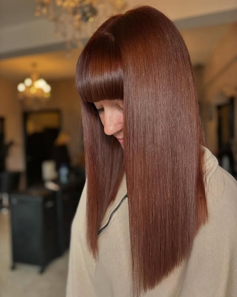 sleek, straight chestnut brown hair with blunt bangs.
