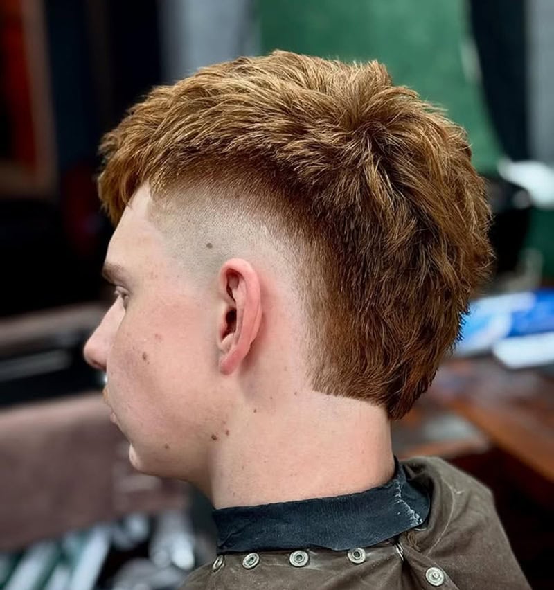 redhead man sporting textured mohawk with a crisp burst fade, showing volume for thick hair