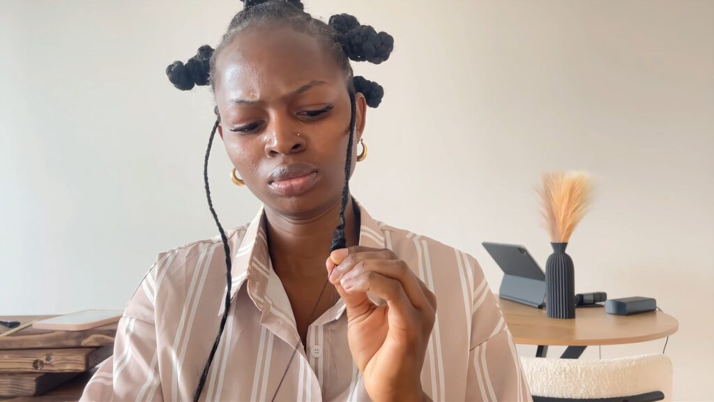The stylist forms a coil at the end of the side braid by wrapping it with thread.