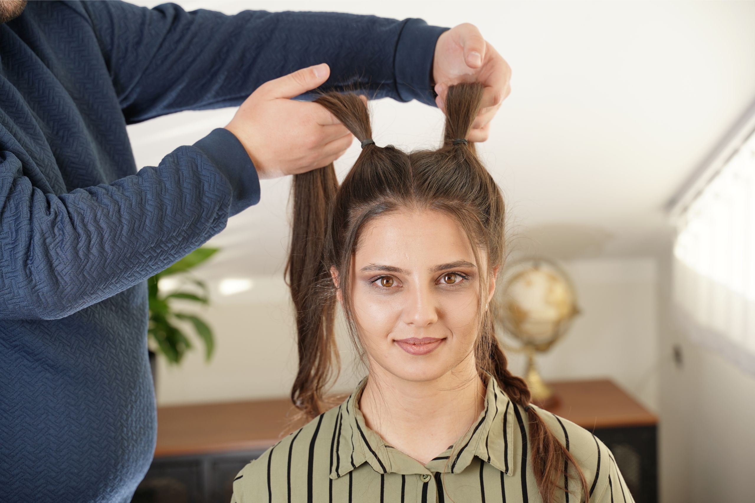 Two upper side sections of hair are secured high with small elastics while small front pieces are left loose.
