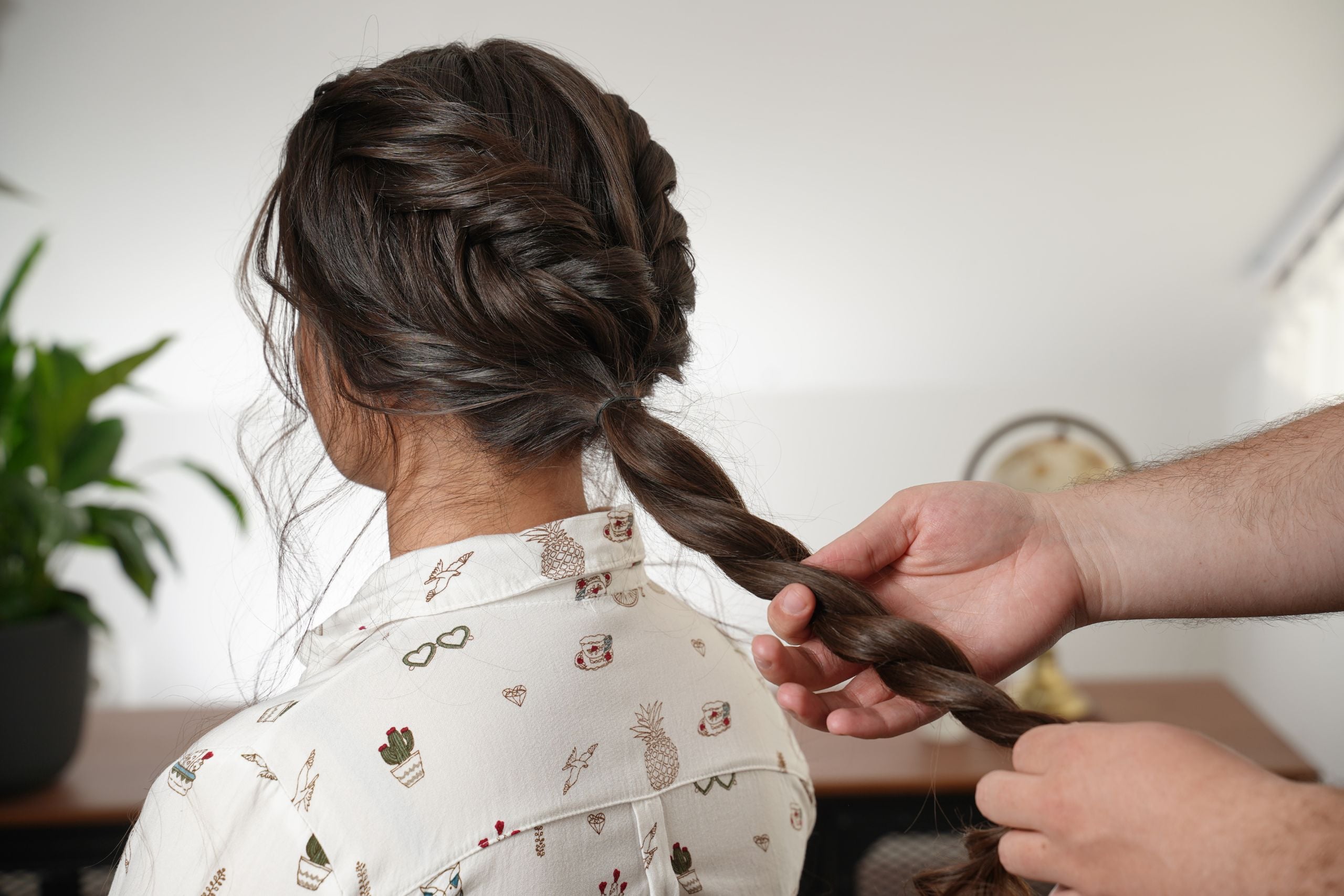 Low ponytail being twisted before wrapping it into a bun for a reverse fishtail braid and flat twist updo.
