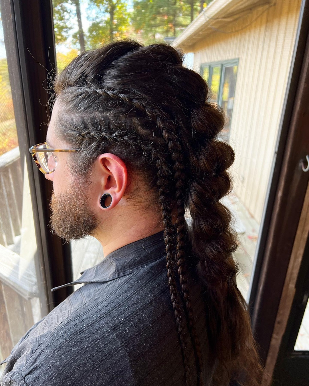 man with long dark hair styled in an intricate braided Viking mohawk with side accent braids