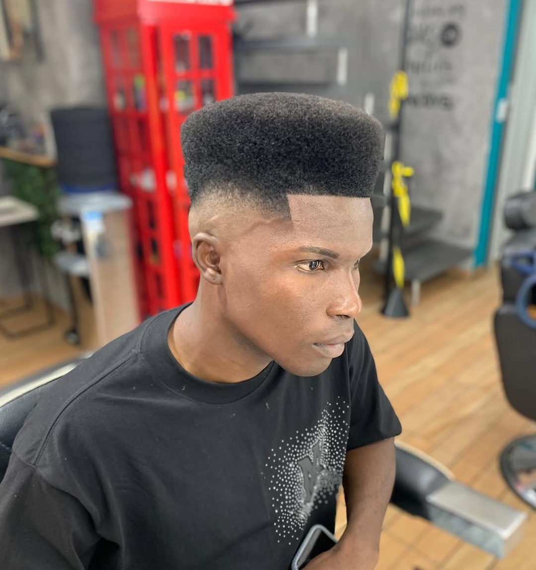 Afro flat top haircut with a sharp lineup and high fade