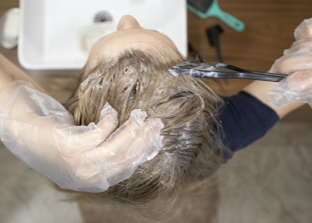 applying cream demi-permanent dye to repigment bleached hair