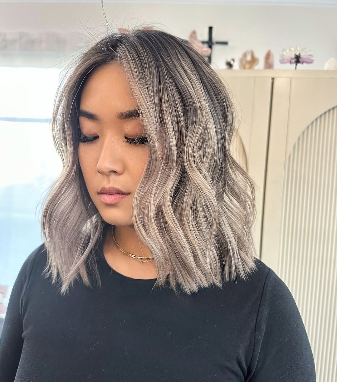 Asian woman with a shoulder length wavy balayage bob in cool ash blonde