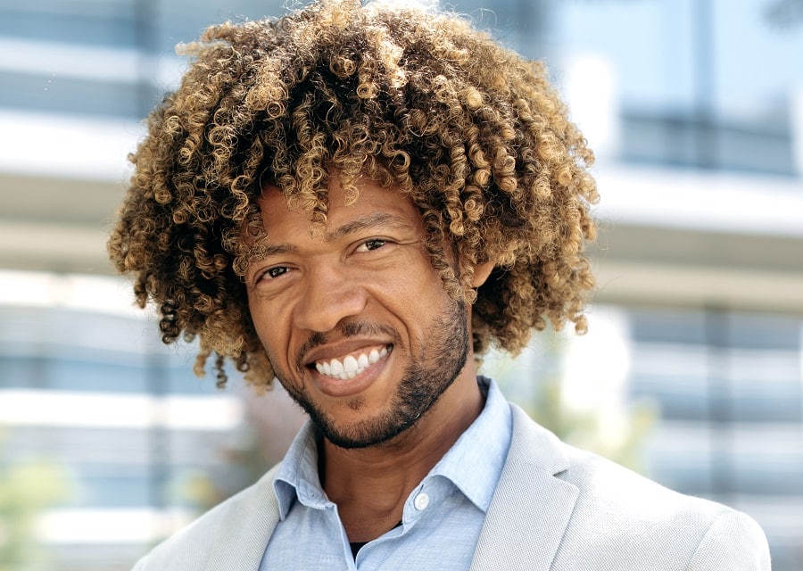 A black guy with curly dark hair and blonde highlights