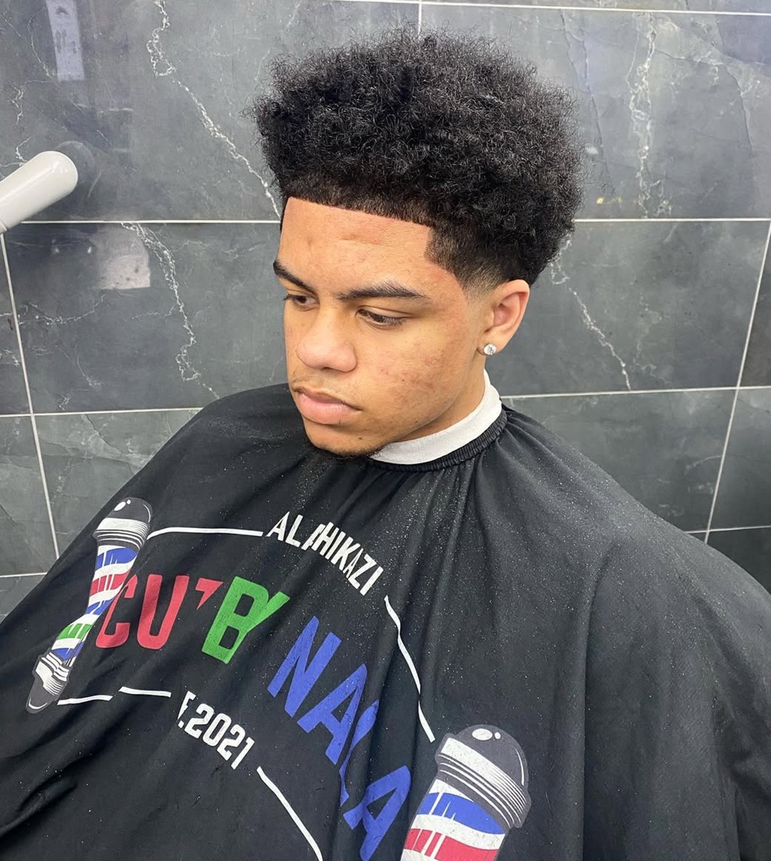 Low taper afro fade haircut on a young Black man with natural short afro hair