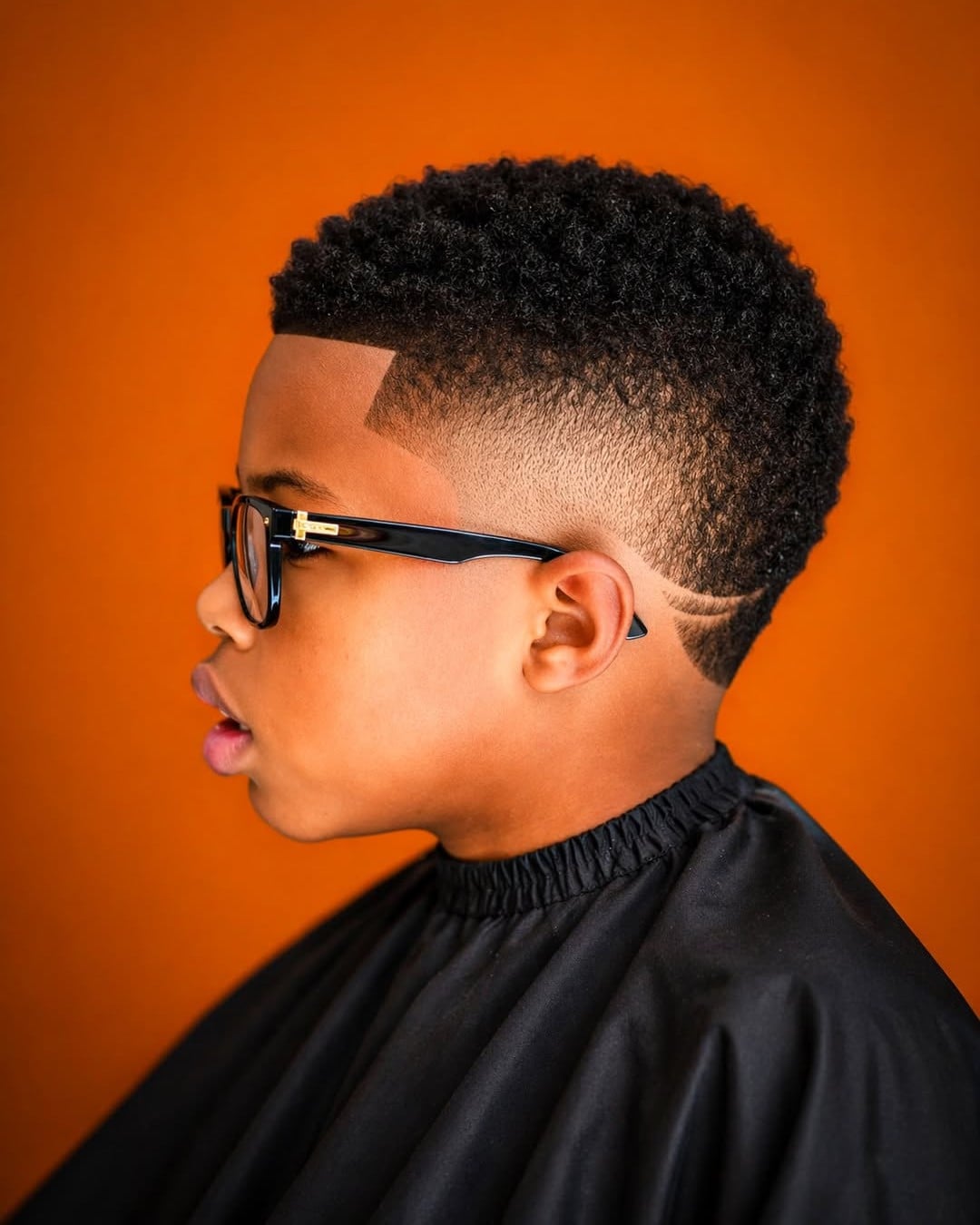 Black kid with a short curly fade haircut and shaved line design