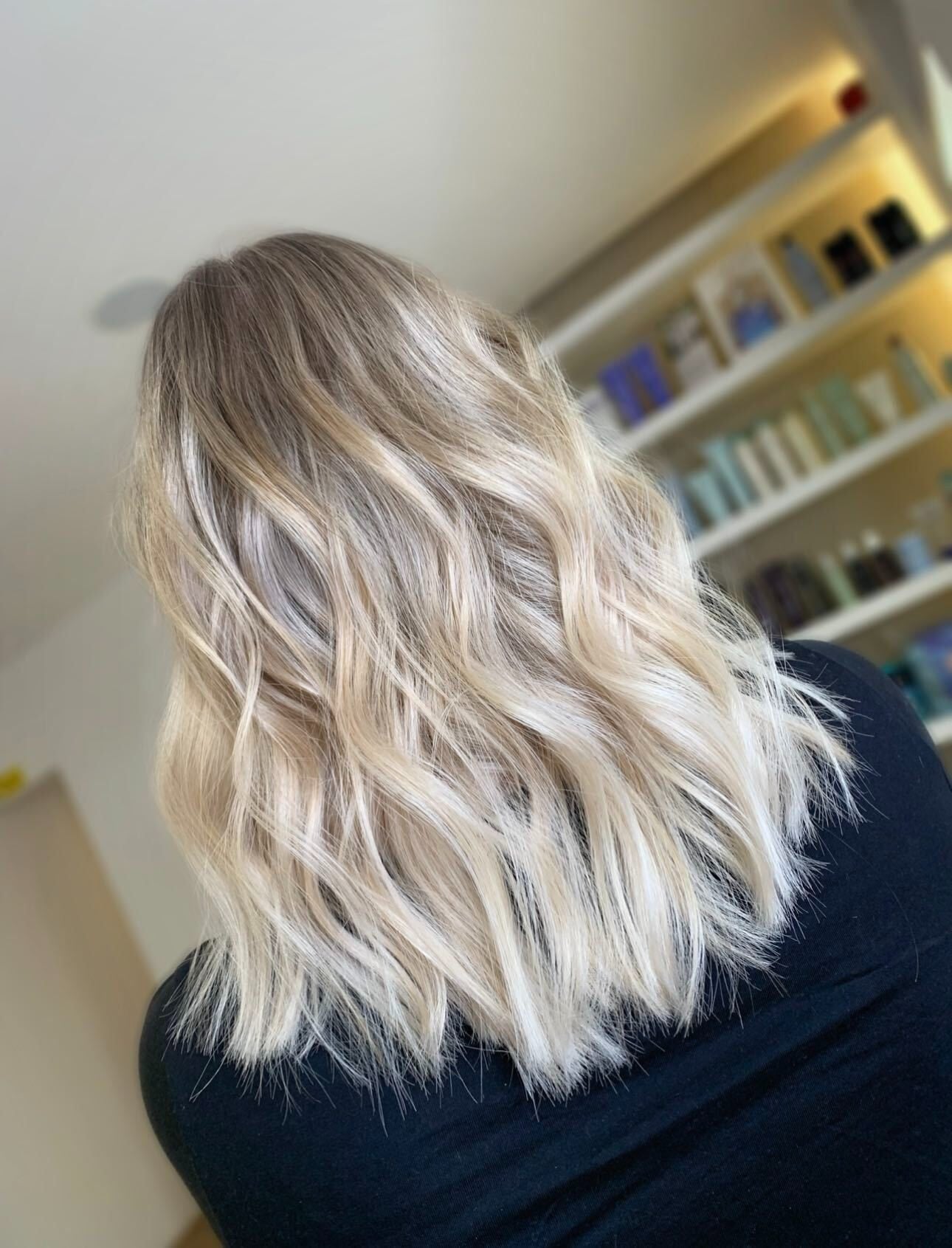 Back view of a shoulder-length blonde haircut with a clean perimeter, styled in soft waves