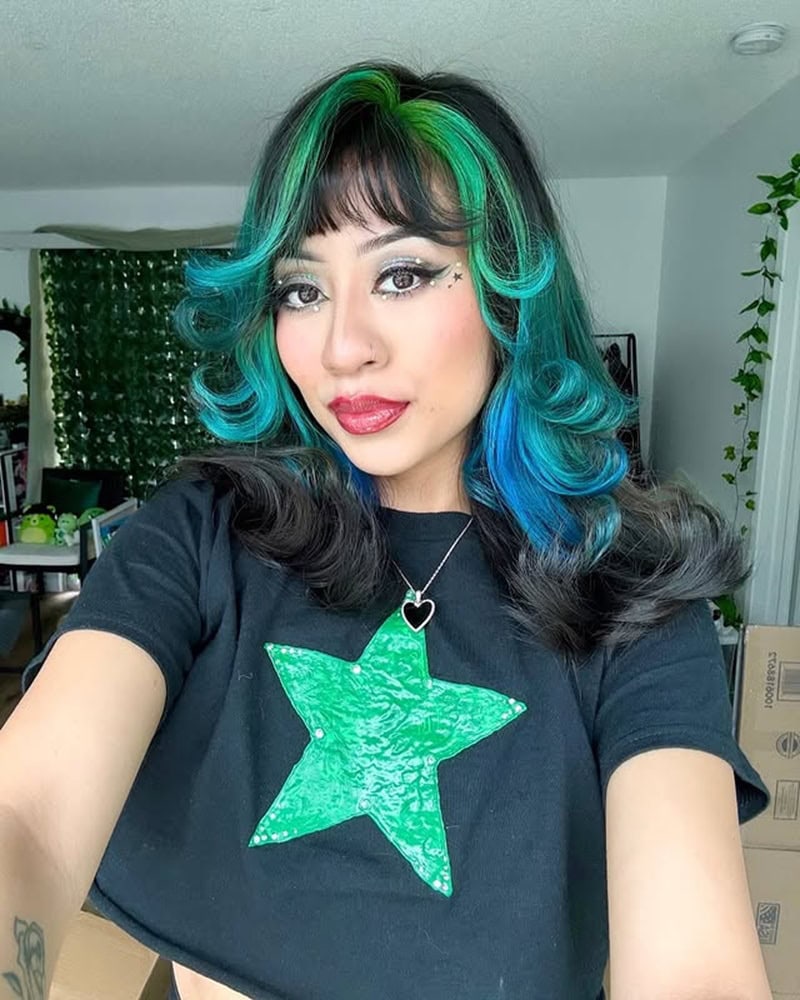Shoulder-length black hair with blue and green face-framing highlights and curled ends