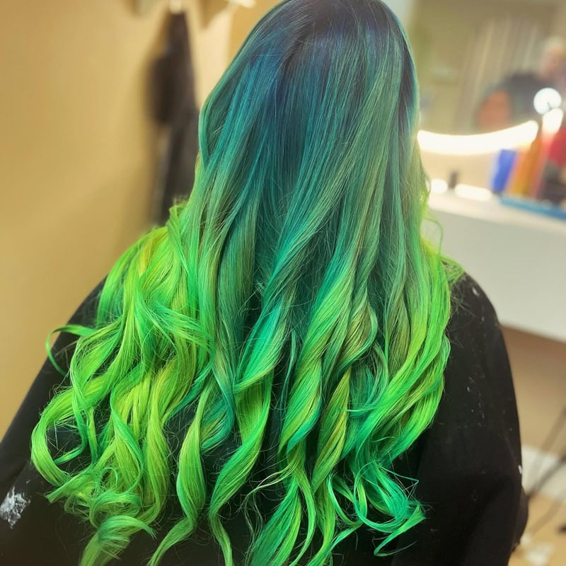 Long loose waves with dark blue roots and neon green ombr&eacute; ends