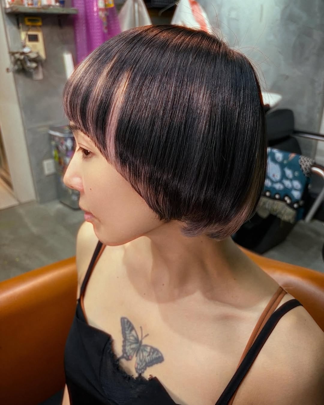dark brown bowl bob haircut with full bangs and subtle pink peekaboo highlights