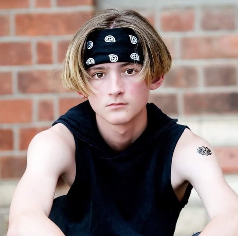 Teen boy with center-parted long blonde hair wearing a black bandana