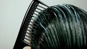 women applying conditioner to his hair with comb