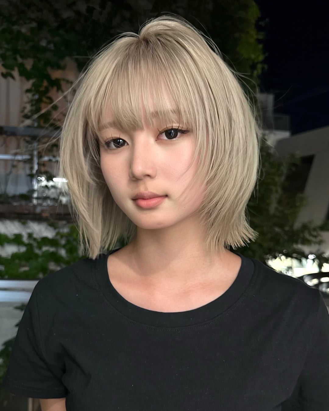 Asian woman with wavy silver blonde lob and curtain bangs
