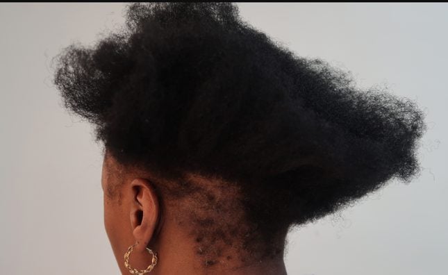 Side view of textured hair with a patch of breakage left by chemical overprocessing